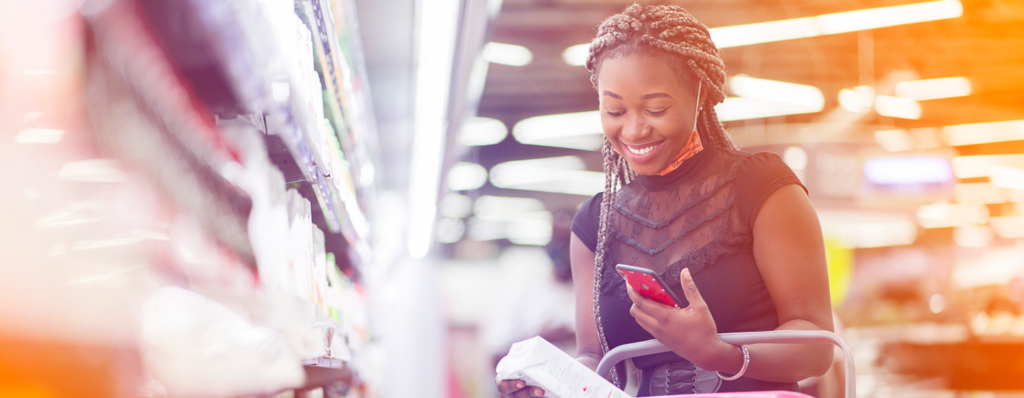 Lady happily shopping while she uses a budget on her phone to avoid unnecessary spending