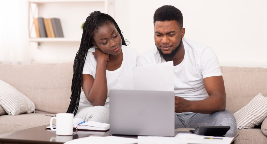 A young couple sorting through their bills to avoid getting their loan rejected