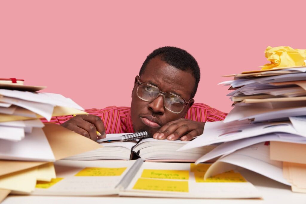 Tired man resting on a table with pile of document